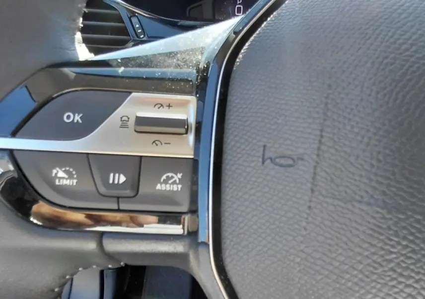 Détail des commandes à gauche du volant cuir noir du Peugeot 408 Hybrid 145 e-DCS6 Allure 2025.