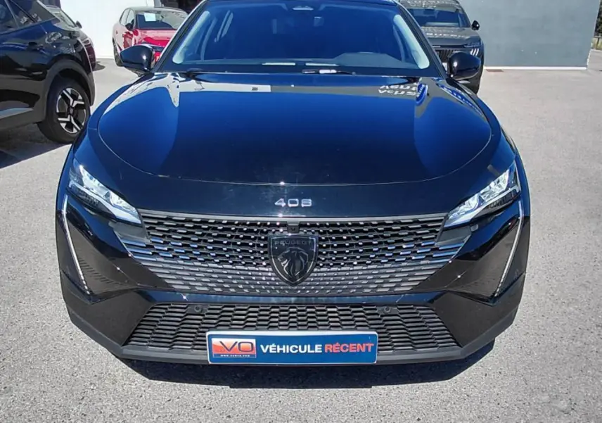 Vue avant d'une Peugeot 408 Hybrid 145 e-DCS6 Allure noire 2025 avec calandre distinctive et phares LED fins.