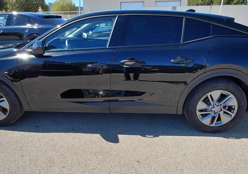 Profil côté gauche de la Peugeot 408 Hybrid 145 e-DCS6 Allure noire 2025 avec ses jantes distinctives en alliage.