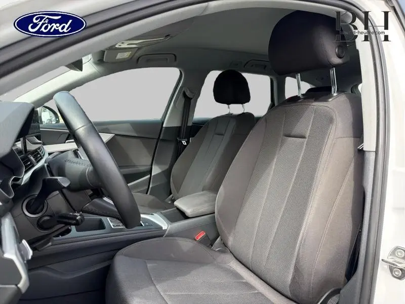Vue intérieure côté conducteur de l'Audi A4 Avant blanc glacier, sièges tissu gris et volant multifonction cuir.