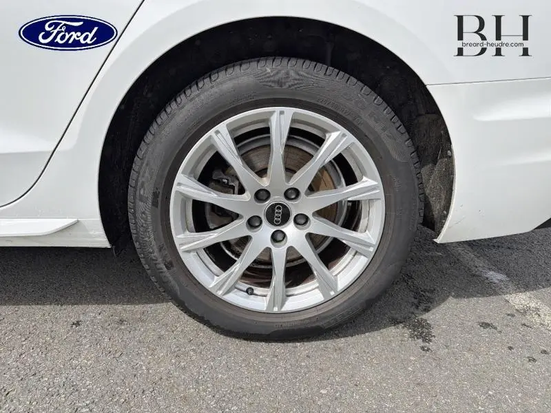 Gros plan sur la roue arrière droite d'une Audi A4 Avant blanc glacier métallisé avec jante alu à 10 branches.