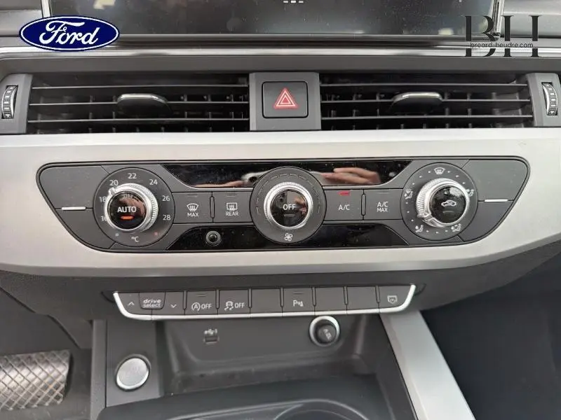 Vue rapprochée de la console centrale grise avec commandes de climatisation et ventilation sur Audi A4 Avant blanc glacier métallisé.