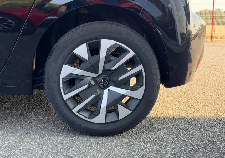 Gros plan sur la roue arrière droite noire Perla Nera d'une Peugeot 208 1.2 100ch avec jante au design géométrique bicolore.