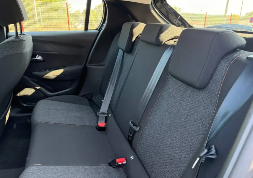 Vue intérieure de la banquette arrière noire avec surpiqûres orange de la Peugeot 208 1.2 100ch Style 2025.