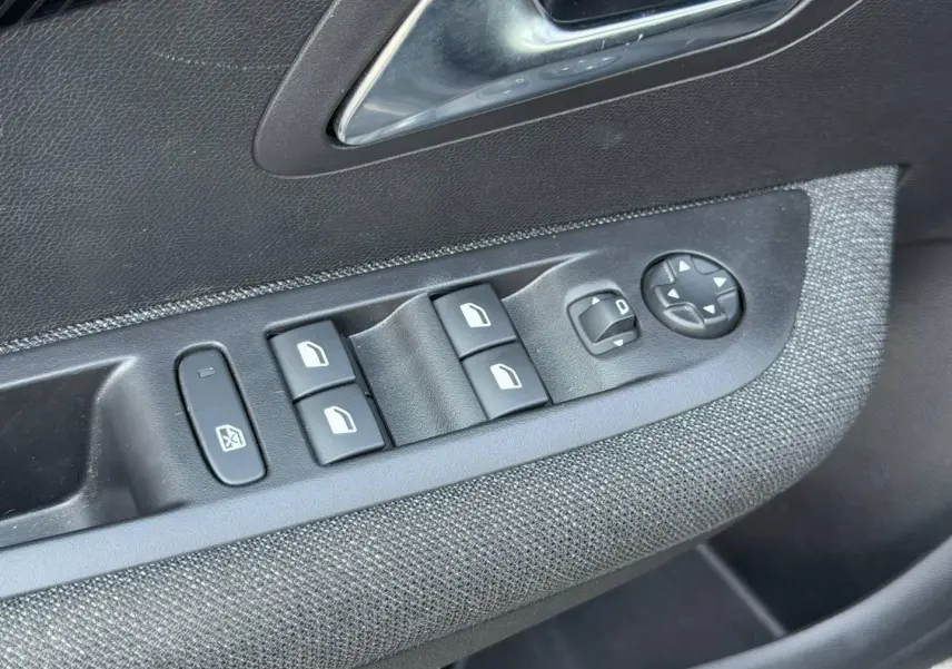 Détail des commandes de lève-vitres et rétroviseurs sur la porte côté conducteur d'une Peugeot 208 Noir Perla Nera.
