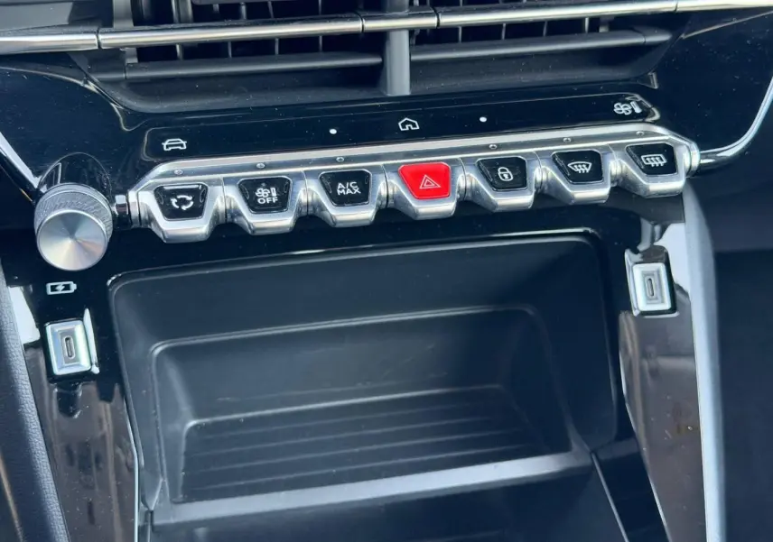 Gros plan sur la console centrale de la Peugeot 208 1.2 100ch Style 2025, boutons argentés et noir laqué.