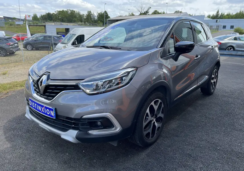 Renault Captur gris en 3/4 avant droit, mettant en valeur ses phares LED et ses jantes alliage distinctives.