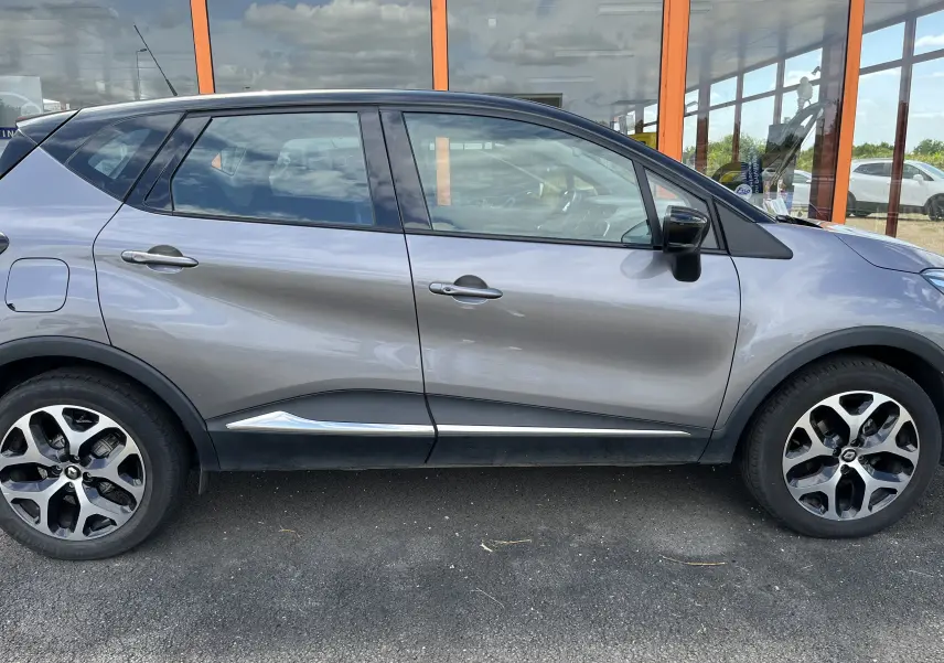 Profil côté droit d'un Renault Captur gris 2019 avec jantes alliage et détails chromés sur les bas de porte.