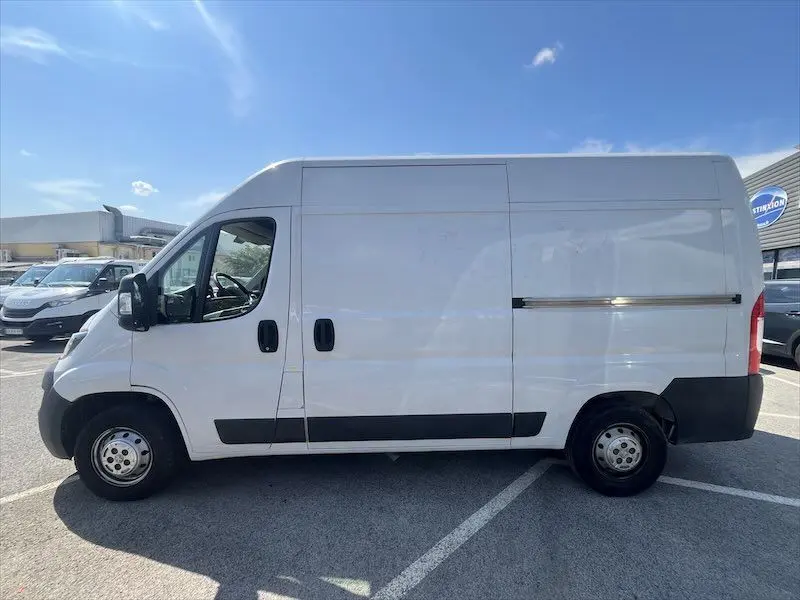 Vue latérale gauche d'un utilitaire Peugeot Boxer blanc avec deux portes latérales, stationné en extérieur.
