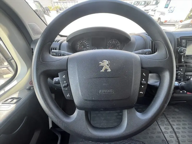 Vue rapprochée du volant noir Peugeot avec logo lion sur un tableau de bord de Boxer FGN blanc, intérieur conducteur.