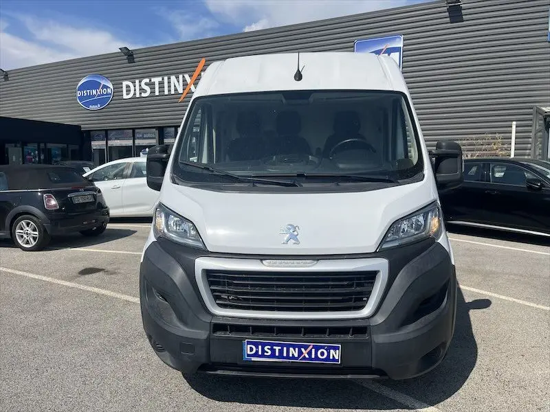 Vue frontale d'un utilitaire Peugeot Boxer blanc stationné devant un bâtiment avec enseigne Distinxion.