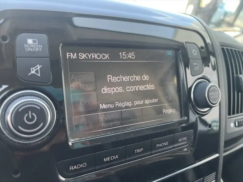 Gros plan sur l'écran tactile du tableau de bord du Peugeot Boxer blanc, affichant la recherche de dispositifs connectés.