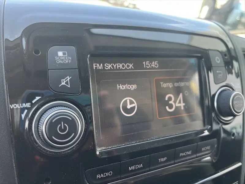 Gros plan sur l'écran tactile du tableau de bord du Peugeot Boxer blanc, affichant la radio FM et la température extérieure.