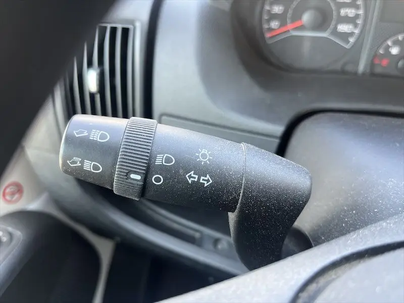 Gros plan sur la commande des clignotants et phares du Peugeot Boxer FGN 2021, intérieur noir avec tableau de bord visible flou.