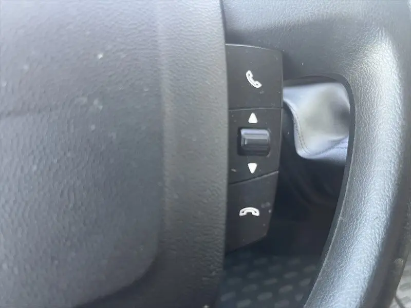 Gros plan sur les commandes téléphoniques au volant noir du Peugeot Boxer FGN blanc, version 2021.