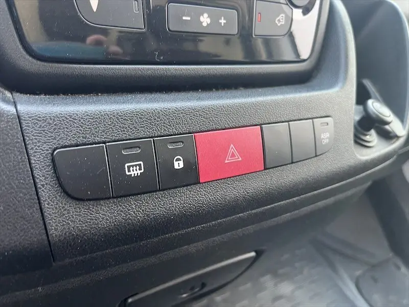 Gros plan sur les boutons de commande du tableau de bord du Peugeot Boxer FGN blanc, avec le bouton d'alerte rouge bien visible.