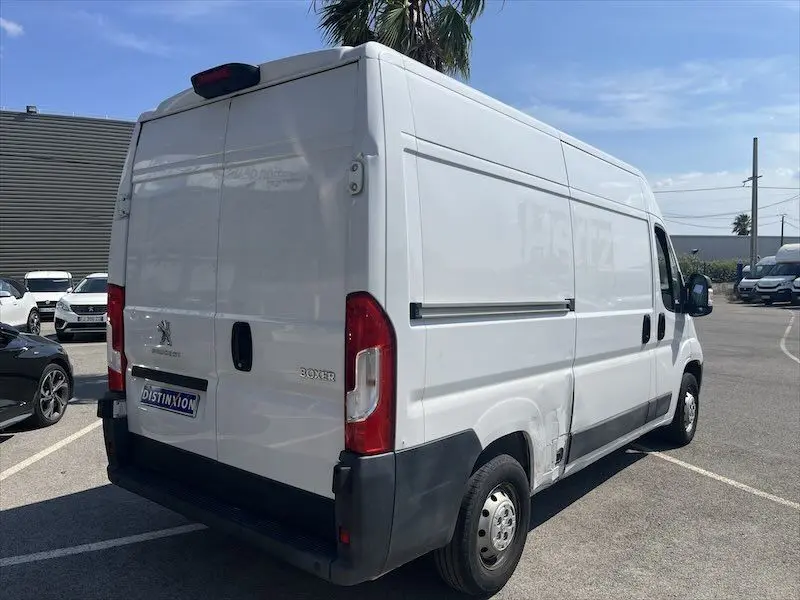 Vue 3/4 arrière droite d’un utilitaire Peugeot Boxer blanc avec deux portes latérales, stationné en extérieur.