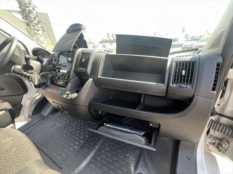 Intérieur côté passager du Peugeot Boxer FGN blanc 2021, tableau de bord avec rangements ouverts et volant à gauche visible