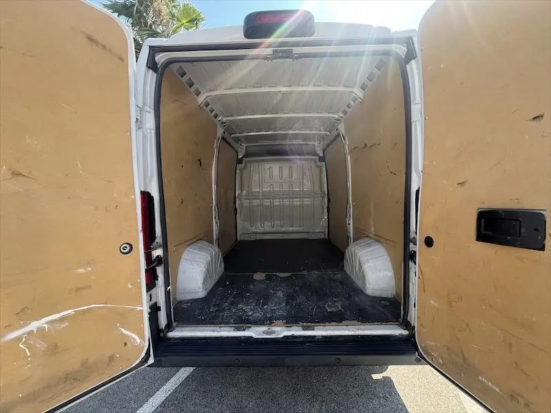 Vue arrière ouverte du Peugeot Boxer blanc 2021 montrant l'intérieur vide et protégé par des panneaux en bois.