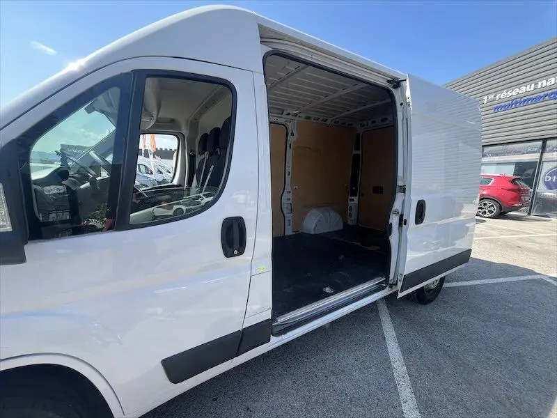 Vue latérale gauche d’un Peugeot Boxer blanc 2021 avec porte latérale ouverte montrant l’espace de chargement vide.