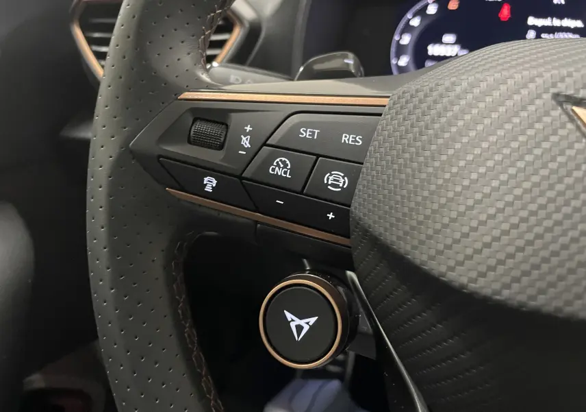 Gros plan sur le volant perforé du CUPRA Formentor 2025 avec commandes intégrées et logo lumineux au centre.