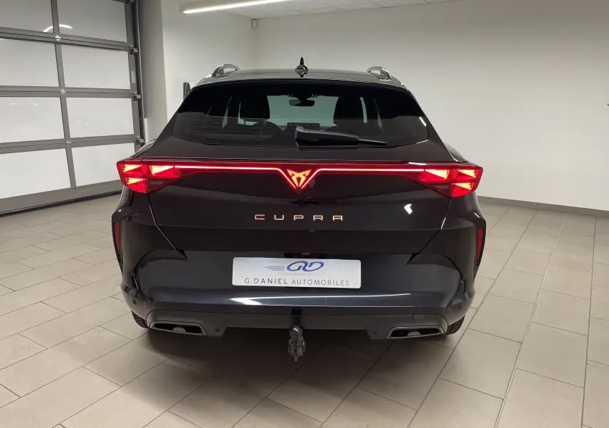 Vue arrière d'un CUPRA Formentor noir minuit avec feux LED allumés et crochet d'attelage escamotable visible.
