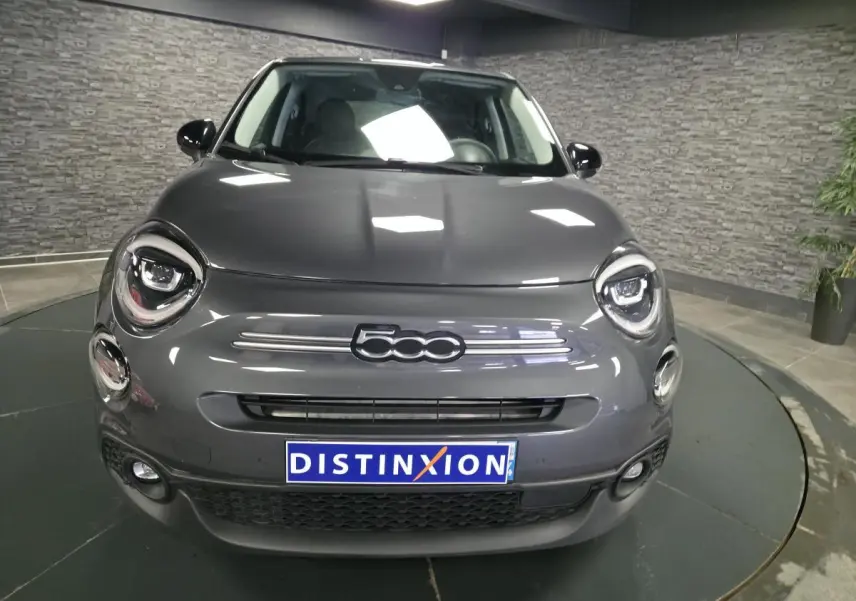 Vue de face d'une Fiat 500X gris métallisé avec phares LED et calandre épurée en intérieur showroom.