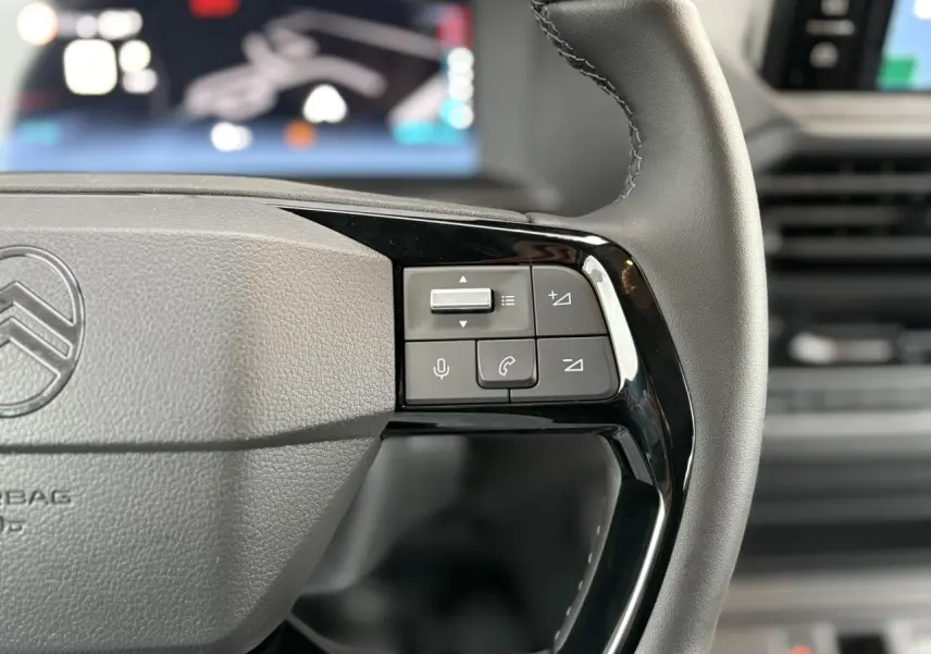 Gros plan sur le volant cuir gris du Citroën Jumpy XL 2025 avec commandes audio et téléphone intégrées.
