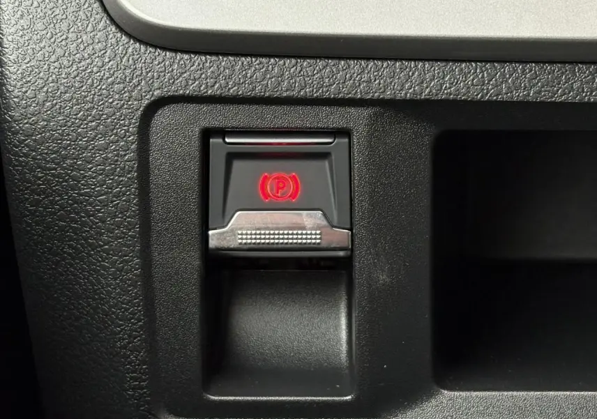 Gros plan sur le bouton de frein de stationnement électrique rouge dans l’habitacle noir du Citroën Jumpy XL 2025.