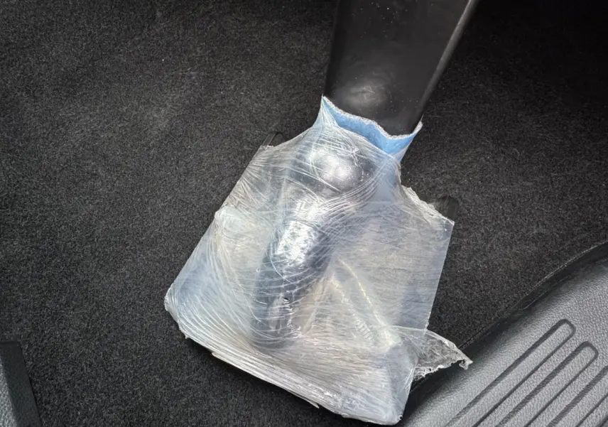 Détail du levier de frein à main noir partiellement protégé par un film plastique transparent dans un Ford Ranger.