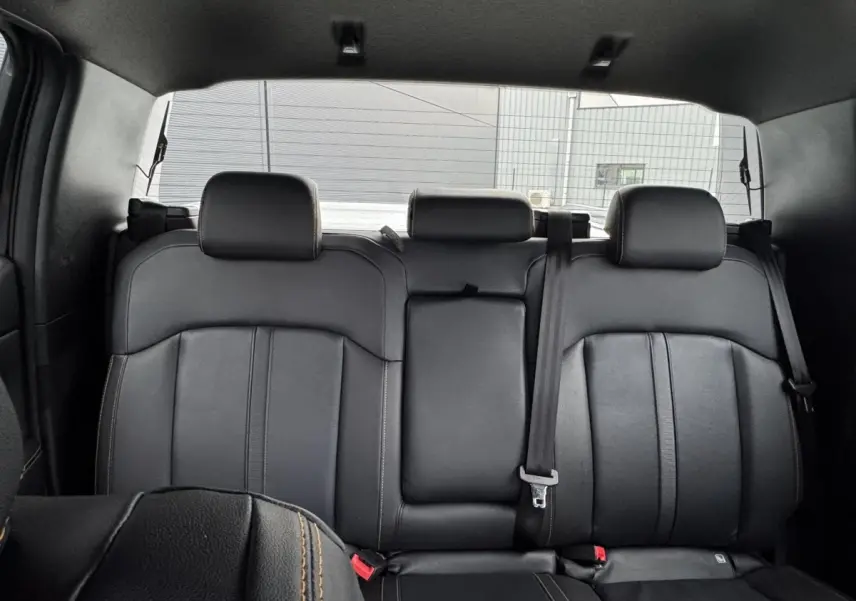 Vue intérieure arrière du Ford Ranger 2025, sièges en cuir noir avec surpiqûres contrastantes et ceinture de sécurité visible.