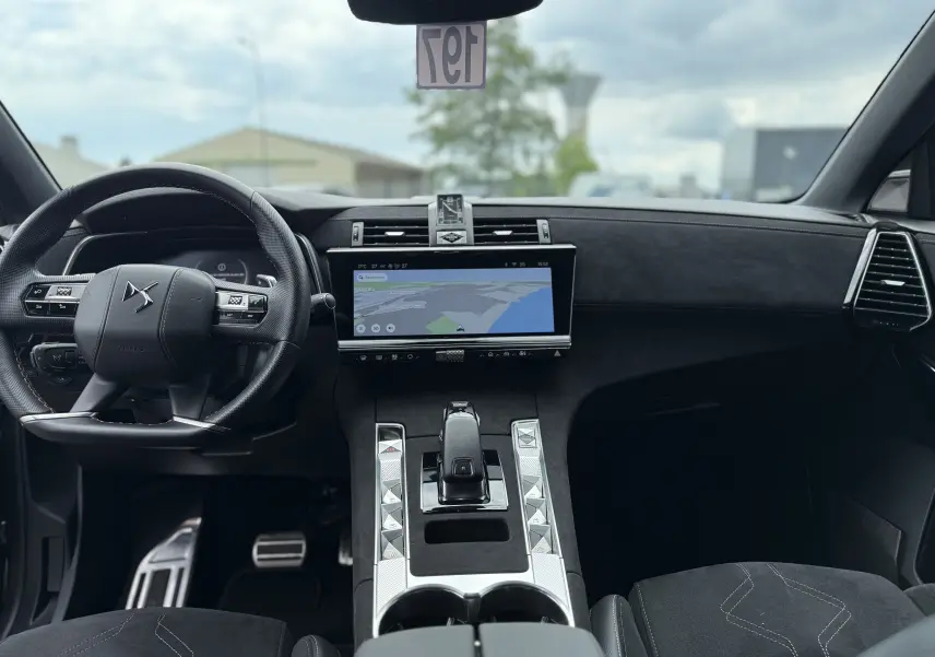 Vue intérieure avant du DS7 BlueHDi 130 Pallas 2025, tableau de bord noir avec écran tactile et volant multifonction.