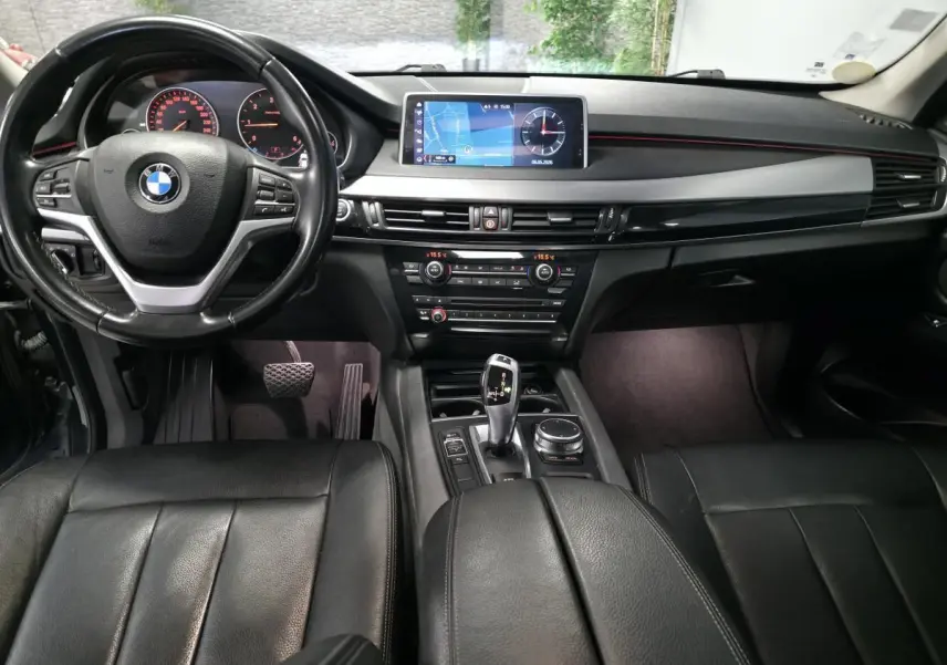 Vue intérieure avant du BMW X5 sDrive 25d 2018 avec sellerie cuir noire et écran de navigation central.