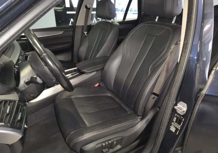 Vue intérieure côté conducteur du BMW X5 sDrive 25d 2018 bleu, mettant en valeur la sellerie cuir Dakota noire et les sièges électriques.