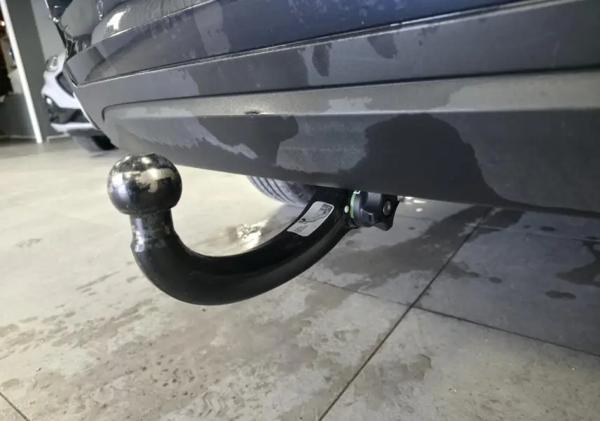 Gros plan sur le crochet d'attelage noir démontable sous le pare-chocs arrière bleu métallisé du BMW X5 sDrive 25d.