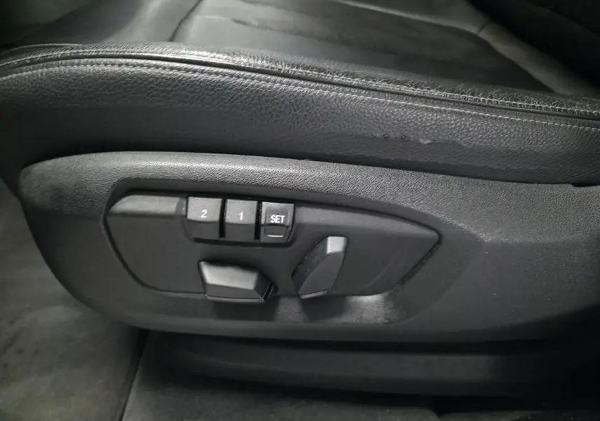 Détail des commandes de réglage électrique des sièges en cuir noir dans un BMW X5 sDrive 25d 2018.