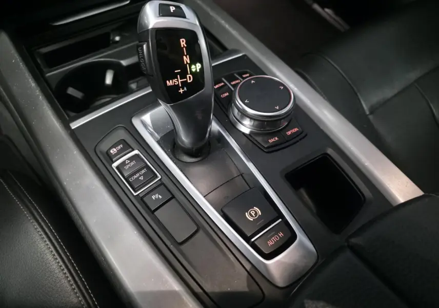 Vue rapprochée de la console centrale avec levier de vitesses automatique et commandes du BMW X5 sDrive 25d bleu.