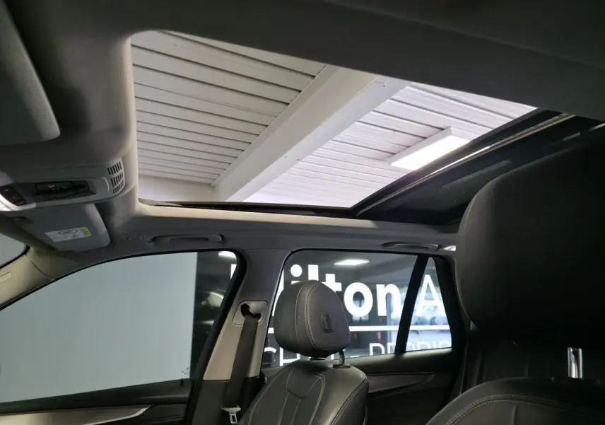Vue intérieure du BMW X5 sDrive 25d 2018 montrant la sellerie cuir noire et le toit ouvrant panoramique en verre.