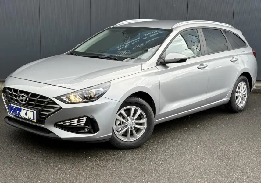 Hyundai i30 SW T-GDI 120 Modern gris argent en 3/4 avant droit, avec jantes alliage et rails de toit visibles.