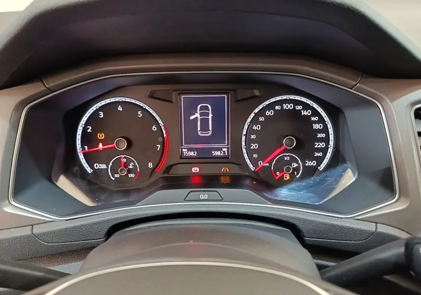 Vue rapprochée du tableau de bord numérique du Volkswagen T-Roc 1.5 TSI bleu, affichant les compteurs et alertes.