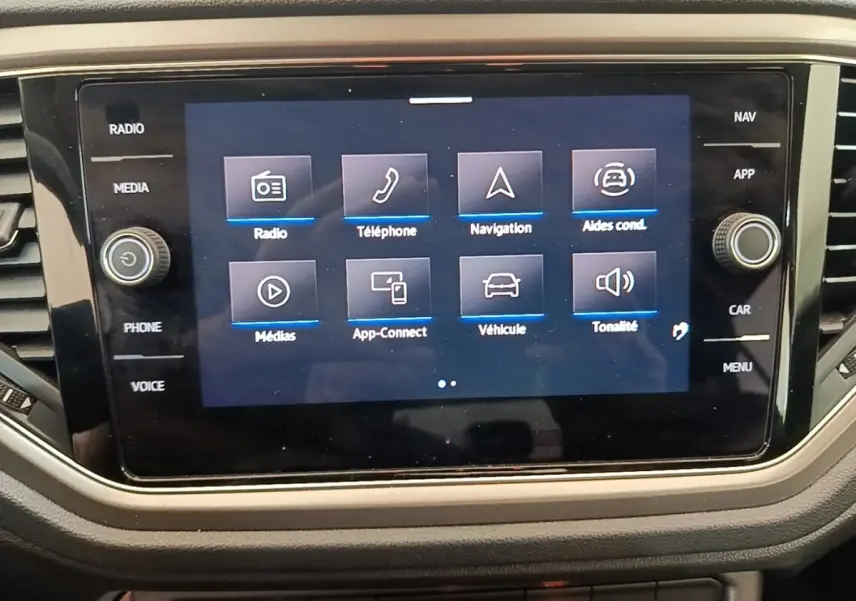 Écran tactile central du Volkswagen T-Roc bleu 2020 affichant les options radio, téléphone, navigation et aides à la conduite.
