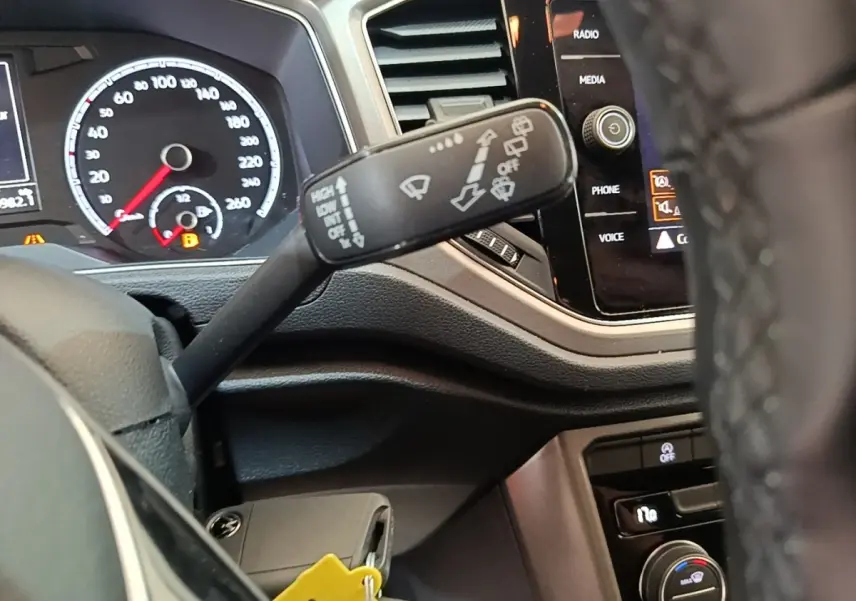 Gros plan sur la manette d’essuie-glace du Volkswagen T-Roc 1.5 TSI, tableau de bord et écran tactile visibles.