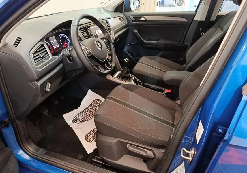 Vue intérieure côté conducteur du Volkswagen T-Roc bleu 2020, montrant tableau de bord et sièges tissu noirs.