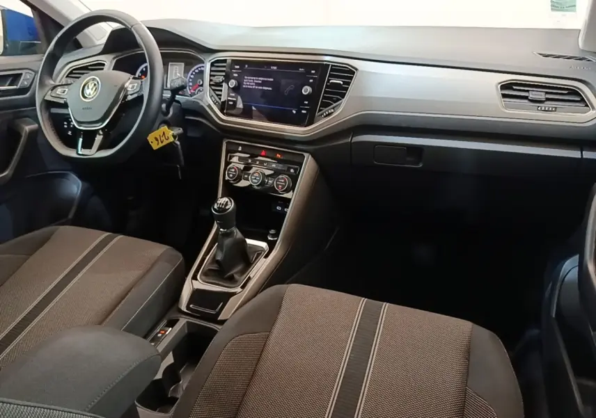 Vue intérieure avant du Volkswagen T-Roc 1.5 TSI 2020, montrant le volant cuir, tableau de bord digital et boîte manuelle.