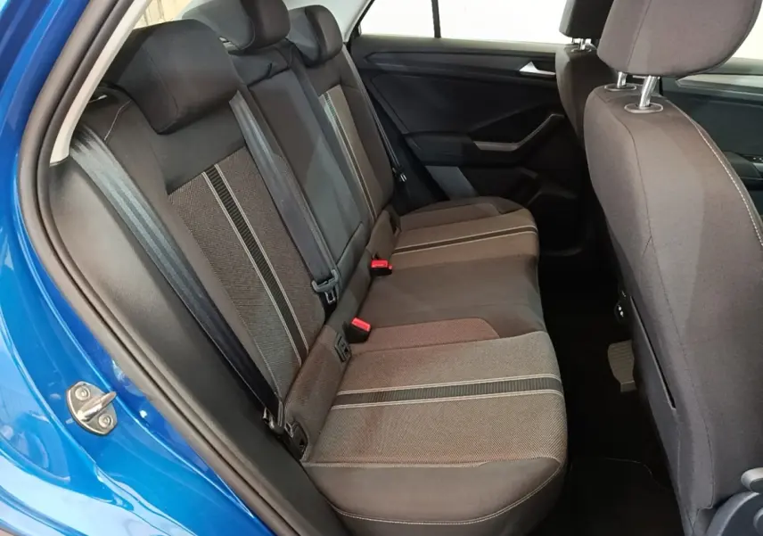 Vue intérieure côté arrière droit du Volkswagen T-Roc bleu, montrant la banquette arrière en tissu gris avec détails rayés.