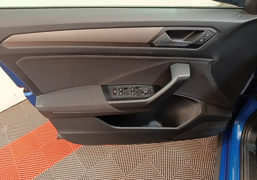 Vue latérale intérieure de la porte avant gauche du Volkswagen T-Roc bleu, avec commandes électriques des vitres et verrouillage.