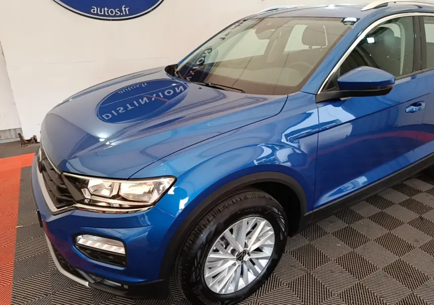 Vue 3/4 avant droit d'un Volkswagen T-Roc bleu brillant avec jantes alliage et rétroviseurs assortis.
