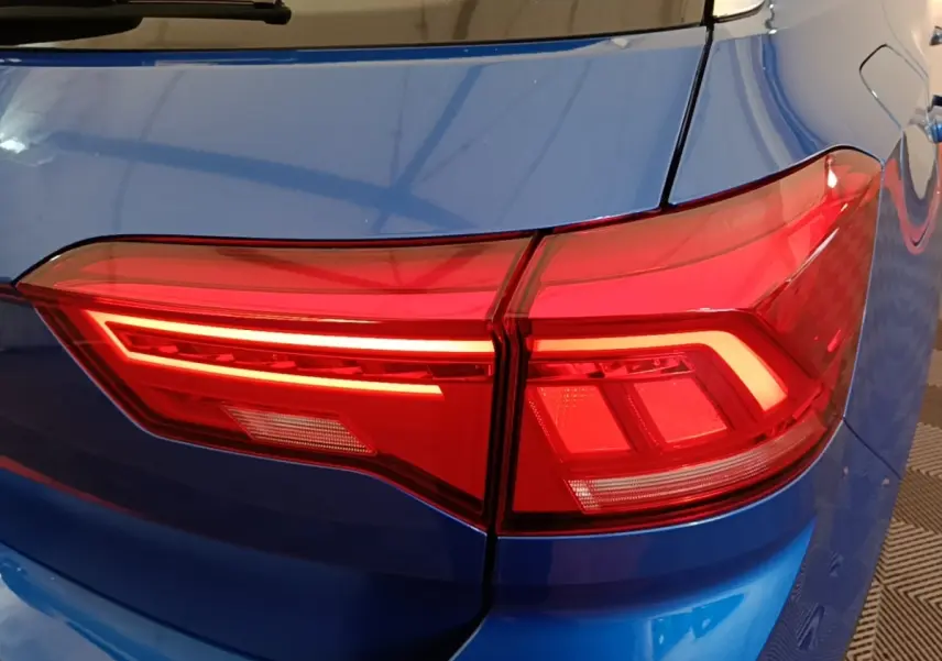 Gros plan sur le feu arrière droit rouge d’un Volkswagen T-Roc bleu 2020, soulignant la carrosserie brillante.