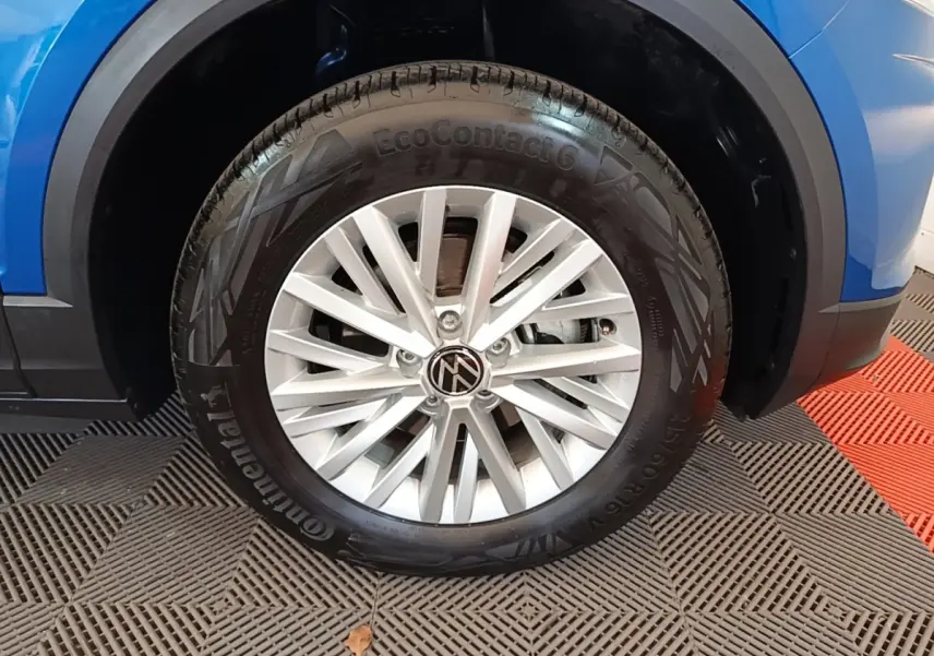Gros plan sur la roue avant droite d’un Volkswagen T-Roc bleu, mettant en valeur la jante alliage et le pneu Continental.