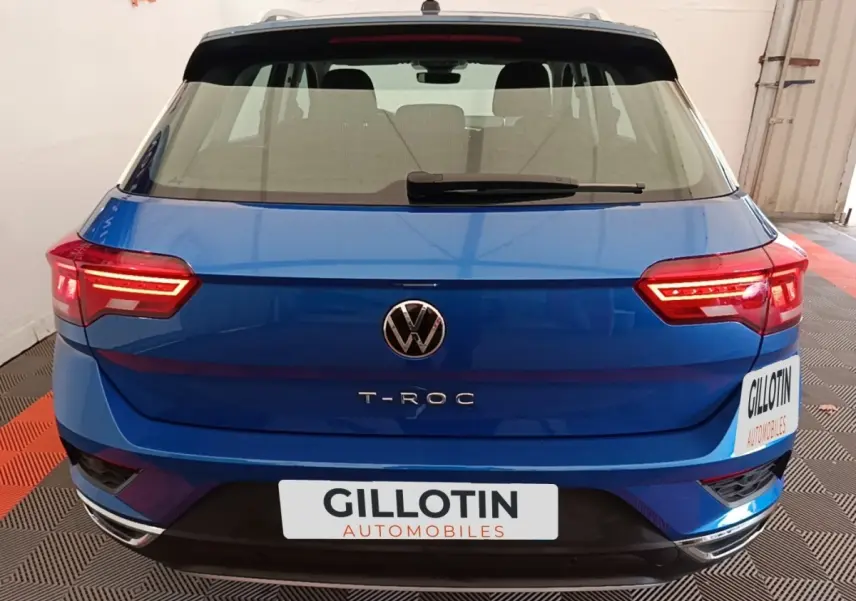 Vue arrière d'un Volkswagen T-Roc bleu 2020 avec feux LED allumés et logo VW bien visible.